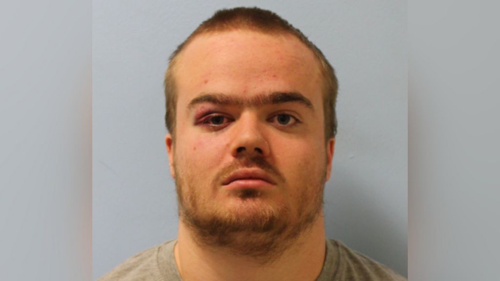 A mugshot of Jonty Bravery, who is wearing a grey shirt. He is staring at the camera and has a beard and short, blonde hair. 