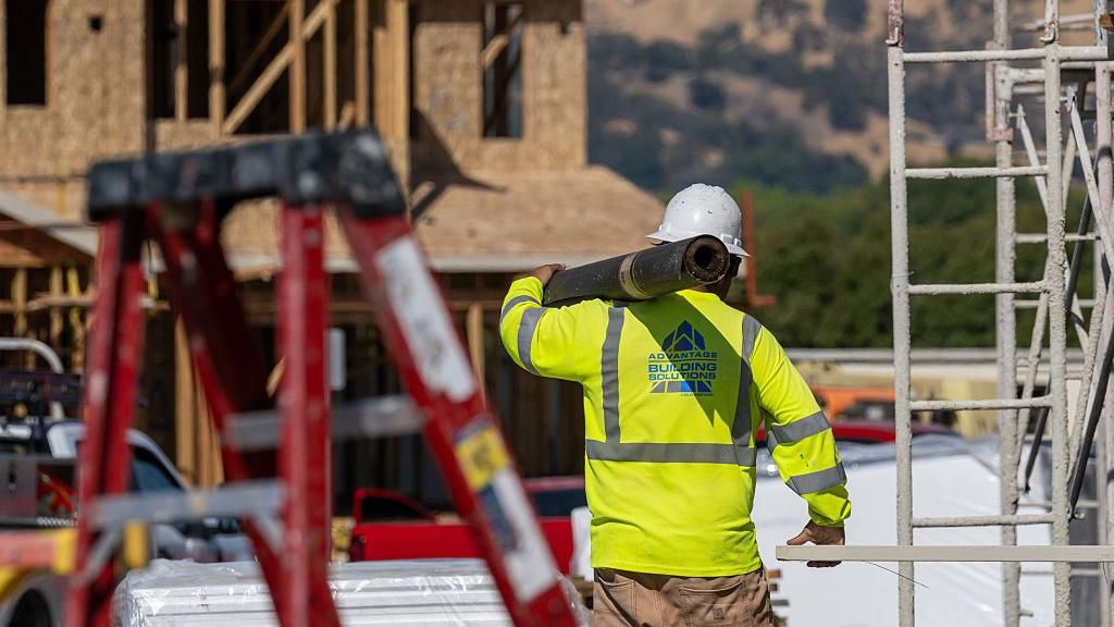 A worker carries materials outside of a new home under construction at the Lilac Ridge community by Lennar Homes in Vacaville, California, US, on Wednesday, Oct. 8, 2025.