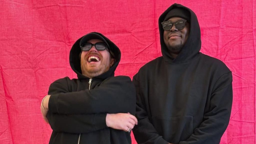 MRCY pictured in front of a pink curtain