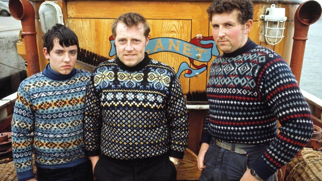 Three Fishermen pose wearing Fair Isle jumpers on the deck of their boat 'Planet' in the harbour of the Shetland Isle of Whalsay in June 1970