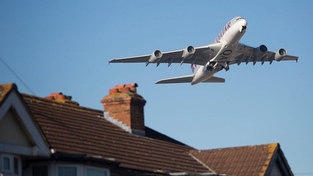 An aircraft flies over homes in Feltham after taking off from Heathrow Airport