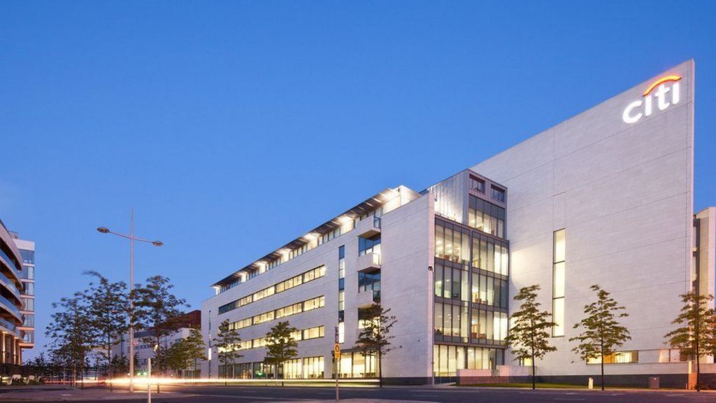Citi's premises at the Gateway building in Belfast's Titanic Quarter. The large five-storey building has a grey facade, big windows and an illuminated "Citi" sign on the top right-hand corner. It dwarfs a number of trees which line the street outside.