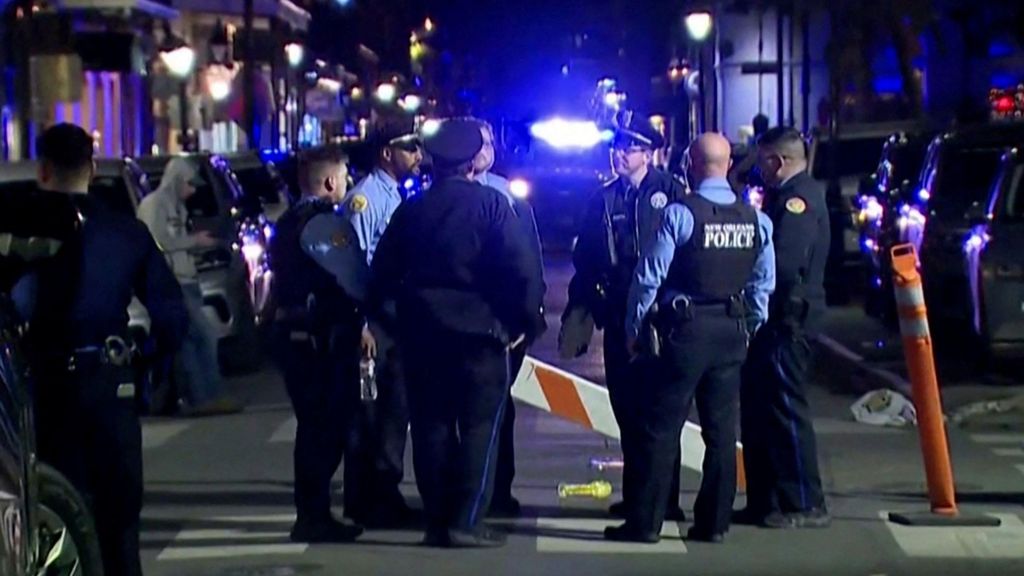 Police stand in dark at attack scene in new orleans.