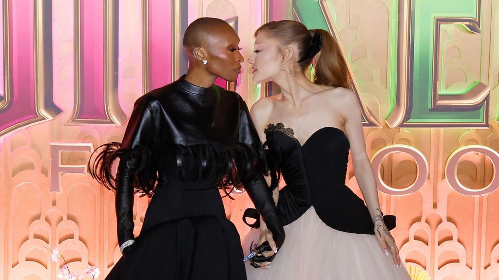 Cynthia Erivo and Ariana Grande holding hands with their faces nearly touching