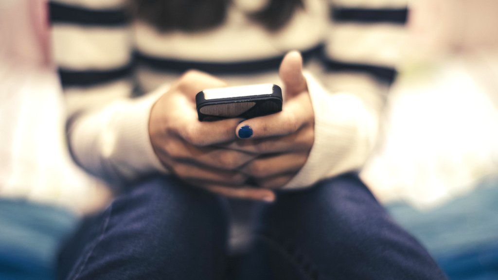 A stock image of a teenage girl using a smart phone with only her hands visible