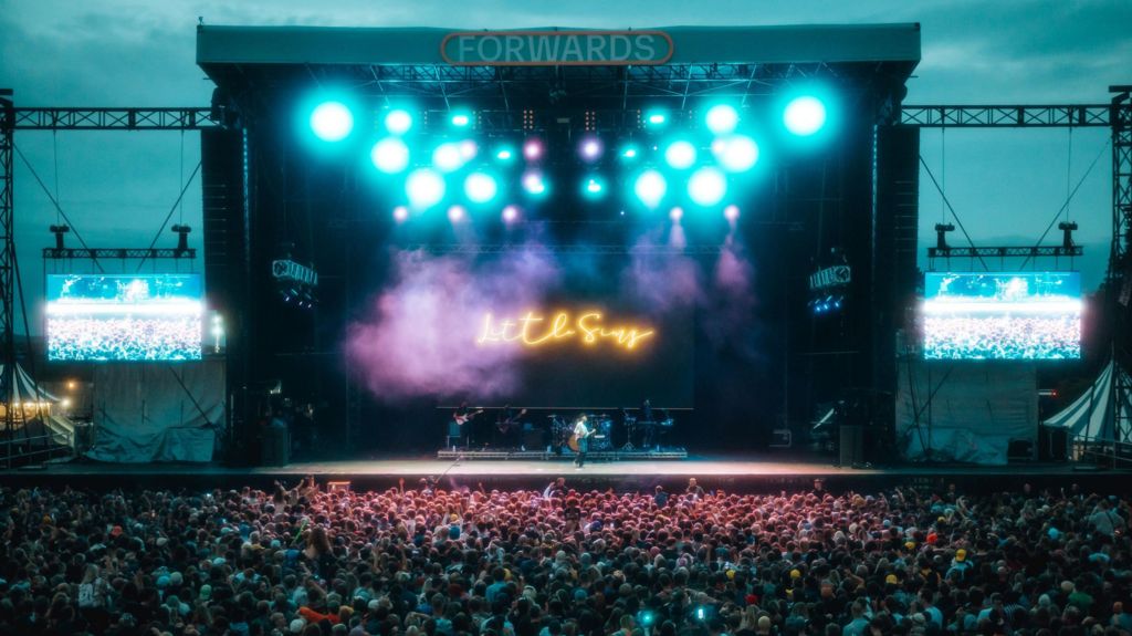 Crowds outside in front of a big stage with lights reading Little Simz