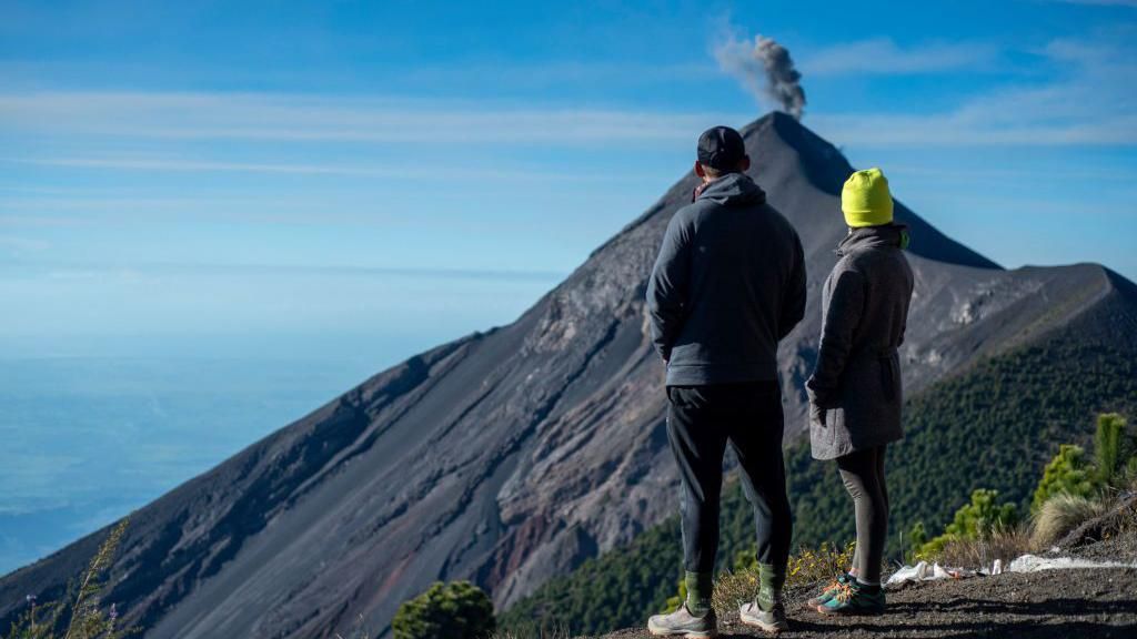 Tourists stood looking at Fuego, a volcano smoking in the background