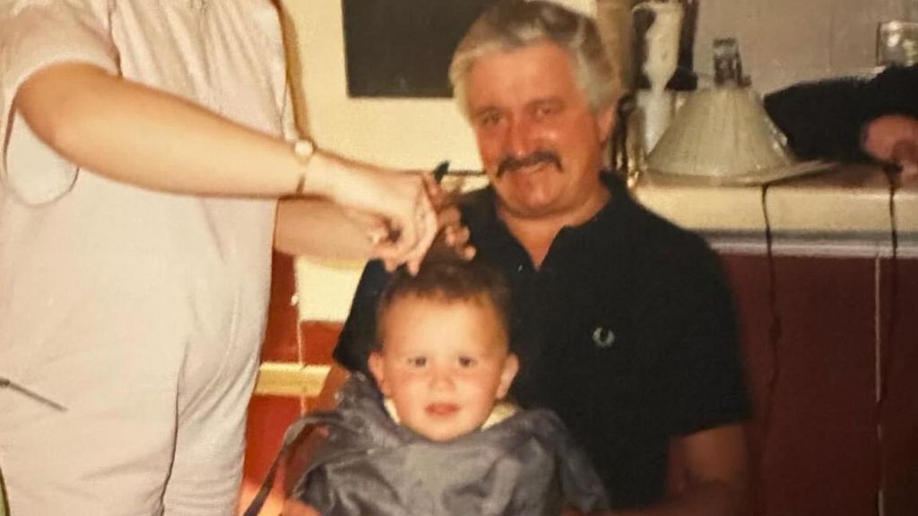 Nick having his first haircut on his father Kenneth's lap