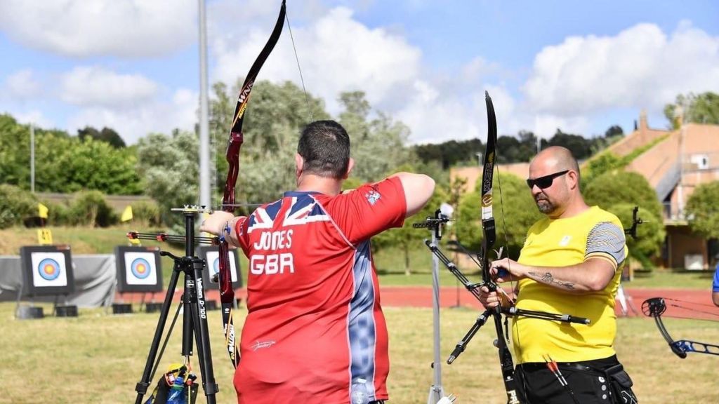 Clive Jones stands ready to shoot his bow and arrow. His spotter stands beside him