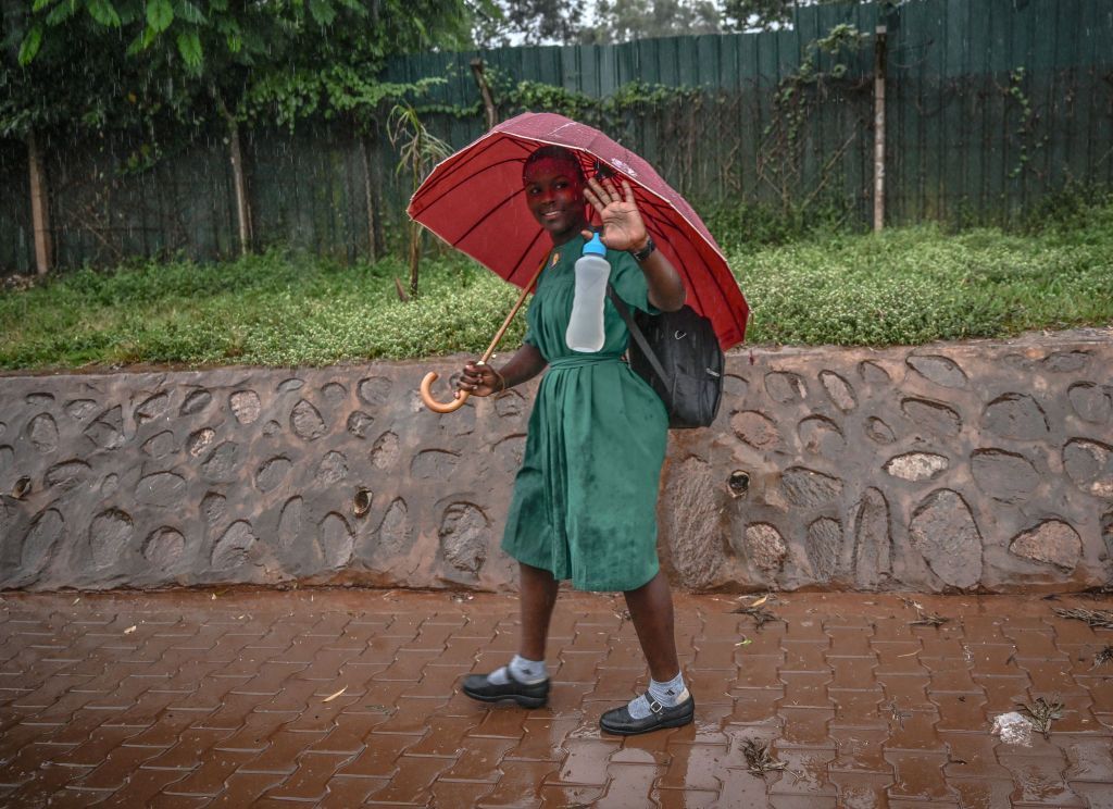 A girl dressed in secondary school uniform walks in the rain in Kampala, Uganda, on Wednesday 24 July 2024