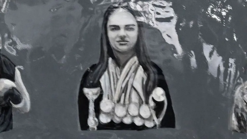 Close up of the helmet showing an image of Karyna Bakhur, who has long hair and has lots of medals hanging from her neck.