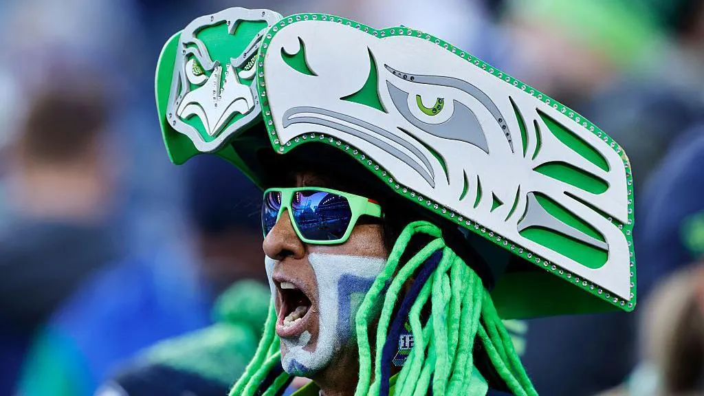 Watts, wearing a sparkling green headdress made to look like the Seahawks logo. He also wears sunglasses and facepaint