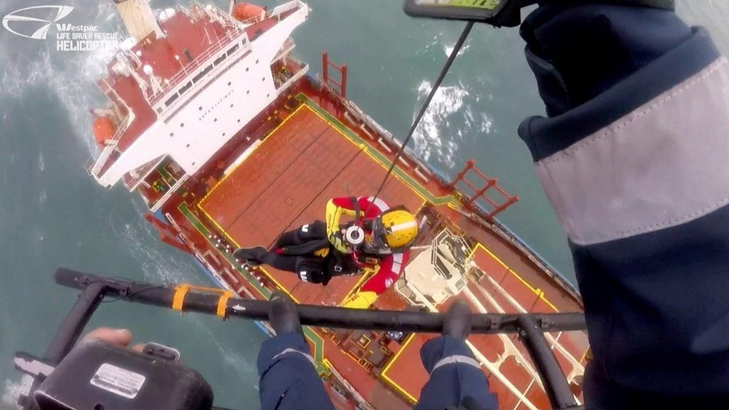 Rescuer being lowered by a wire on to a cargo ship
