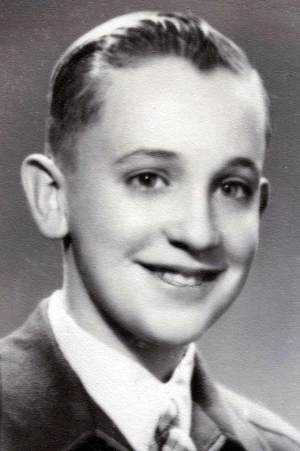 Jorge Mario Bergoglio is shown in a black and white school photo. He is smiling.