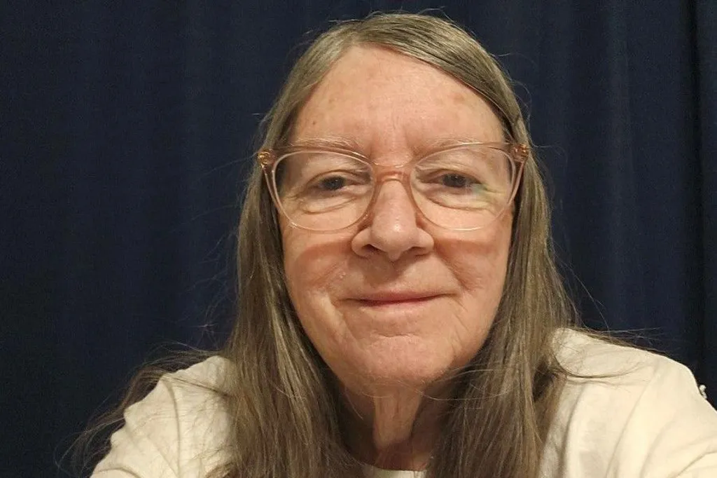 A woman wearing glasses poses for a selfie.