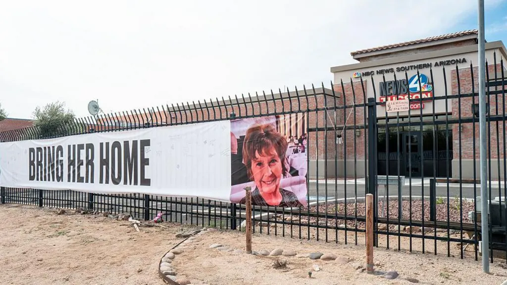 A banner hung on the gate outside a local NBC affiliate shows a picture of Nancy Guthrie and reads: Bring Her Home