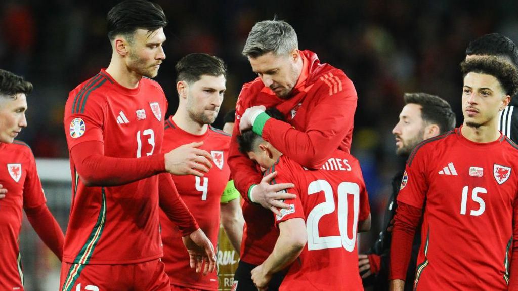 Daniel James is consoled by his team-mates after his penalty shootout miss against Poland 