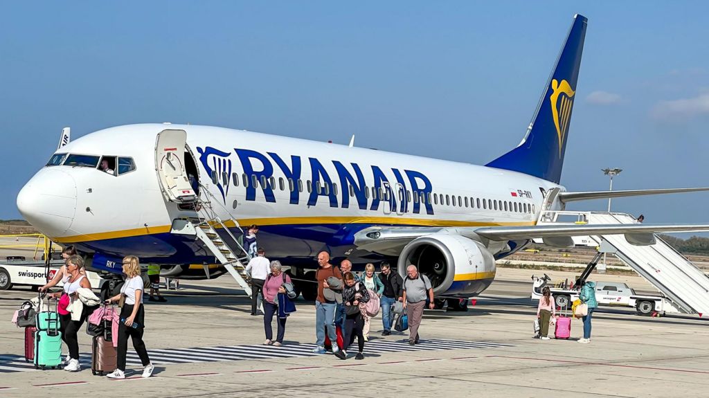 A Ryanair plane with passengers getting off and walking across the tarmac.