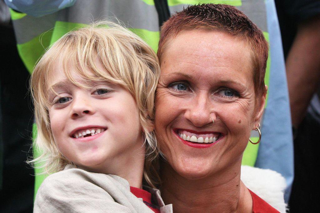 Parys Lapper cuddles his mother Alison in 2005. Parys is aged five and is smiling. He has long blonde hair and is wearing a beige jacket and red t-shirt. Alison has short hair, a nose piercing and gold earrings. She is smiling.