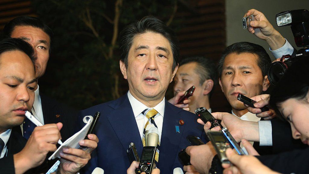Japanese Prime Minister Shinzo Abe (C) speaks to reporters