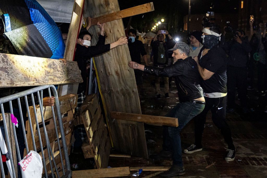 Protesters fight with counterprotesters around makeshift barricades made of wood and metal