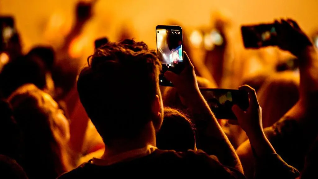 A crowd film a concert on their phones
