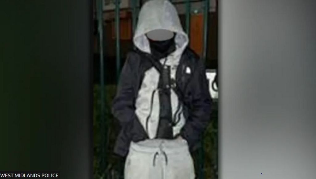 A boy with a tracksuit on, face obscured, and a large knife in the front of his trousers