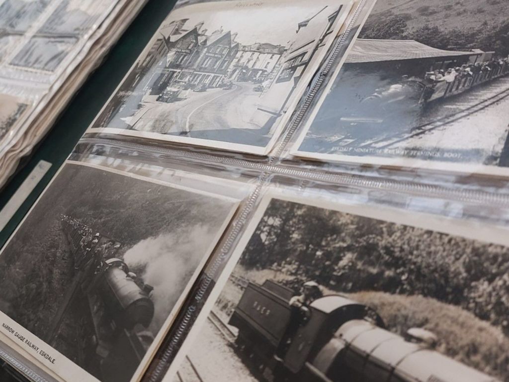 Black and white postcards showing a high street and trains