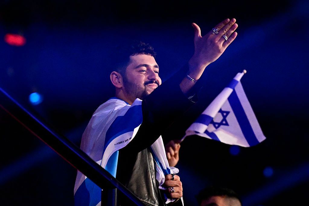 Noam Bettan, carrying an Israeli flag, waves to the audience at Vienna's Wiener Stadthalle