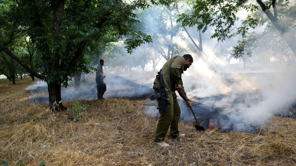 Israeli first responders use shovels to put out flames near Kiryat Shmona on 4 June 2024