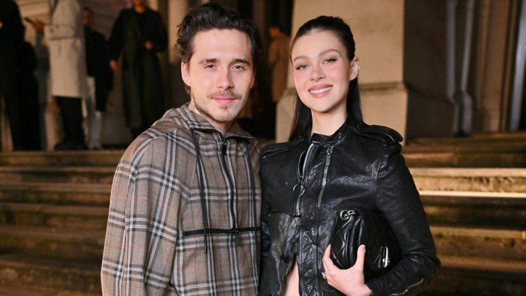 Brooklyn and Nicola Peltz Beckham at Burberry's winter show in 2025, they are both wearing the classic Burberry check