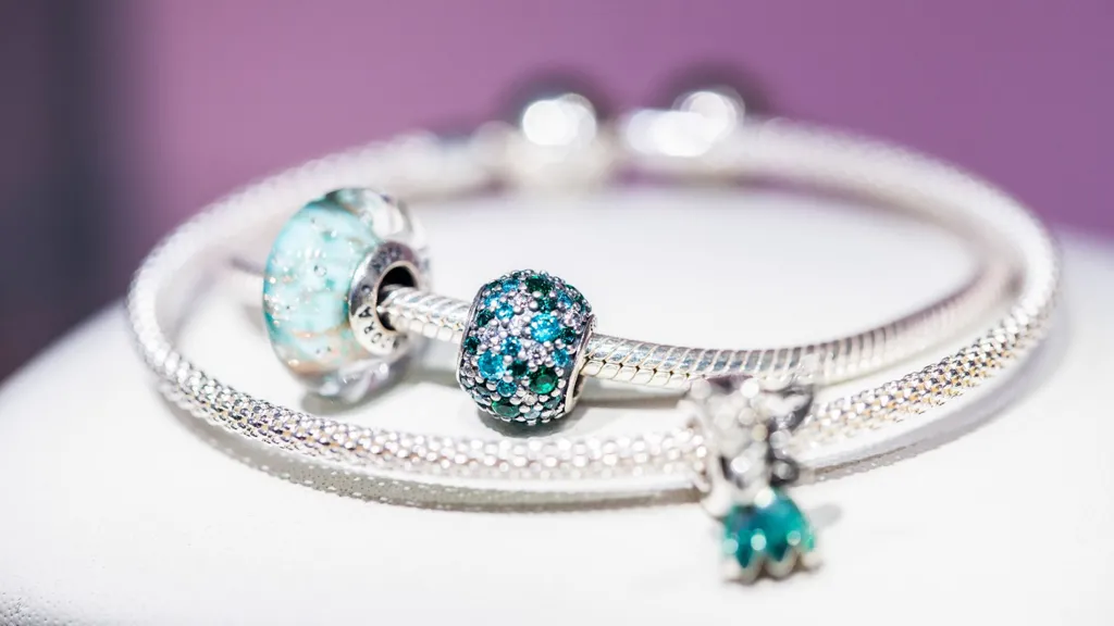 A Pandora charm bracelet with bright turquoise stones and a silver band.
