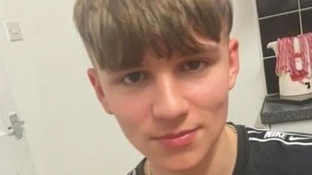 A boy with brown hair and wearing a black Nike t-shirt.