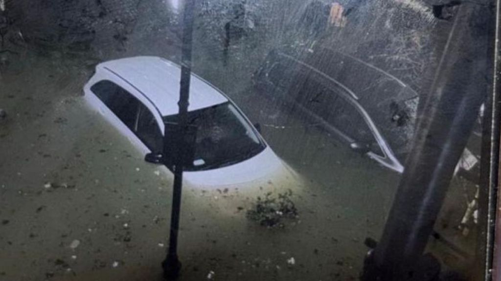 A white car is surrounded by water. The photo was taken at night from above.