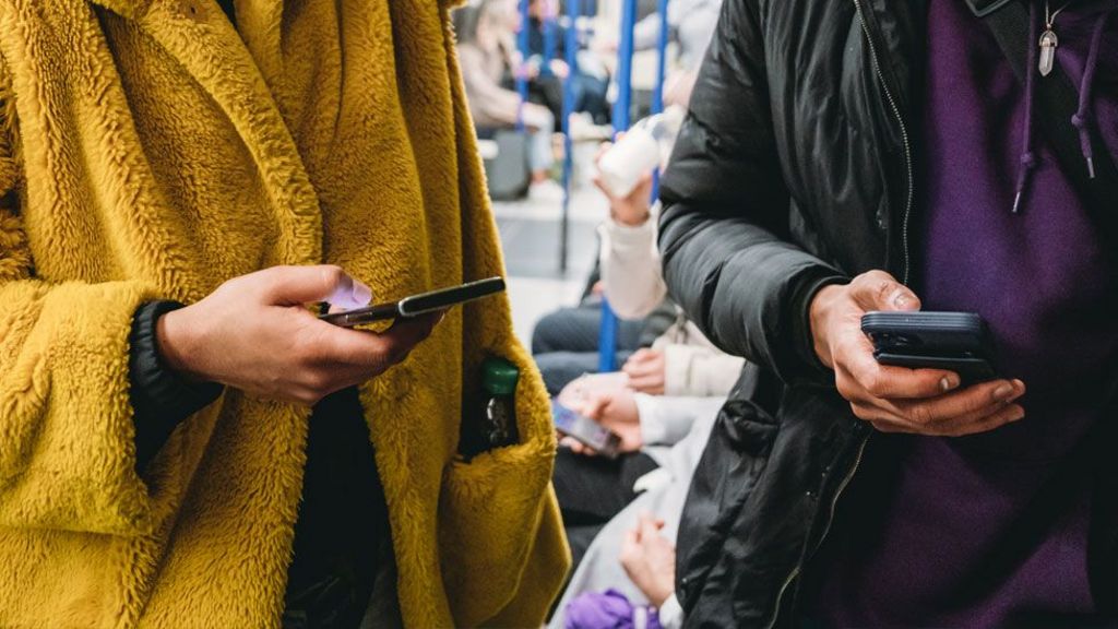 Travellers use their mobile phones on a train