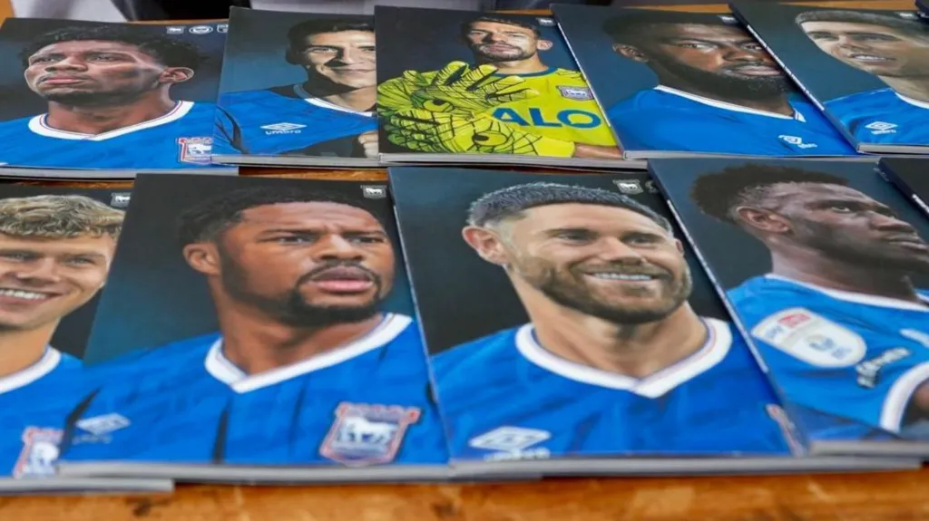 Nine portraits of Ipswich Town FC male players lying on a table in two rows. 