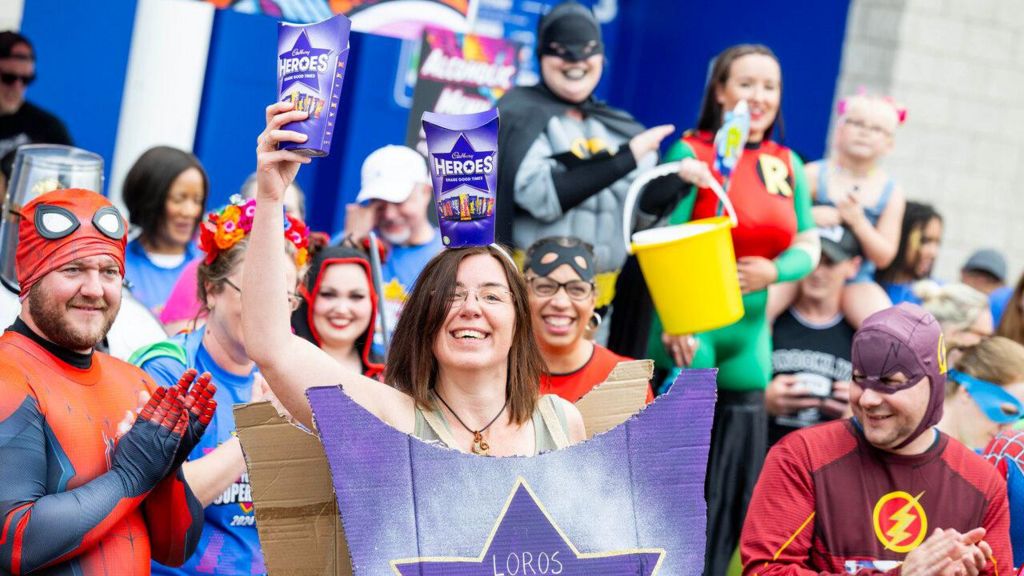 A woman dressed as a box of heroes surrounded by other people in costume