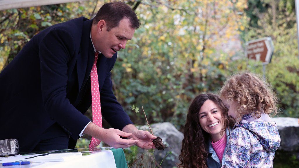 Deputy minister for climate change, Lee Waters, giving tree sapling to a local family