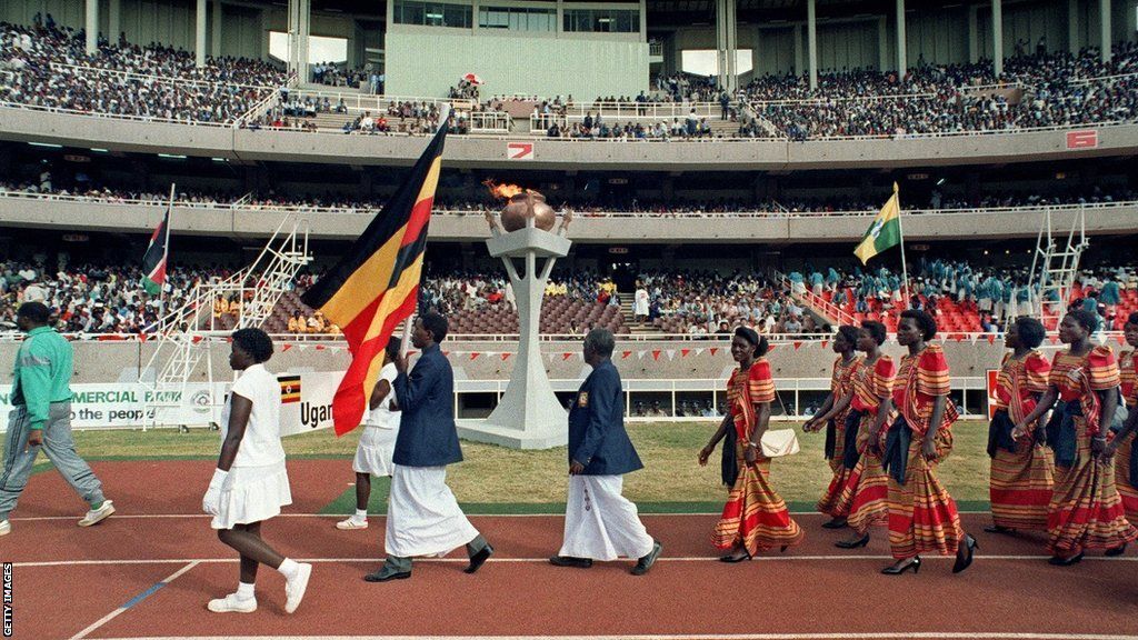 Representatives of Uganda carry a flag and walk around the track in Nairobi at the opening ceremony of the 4th All African Games.
