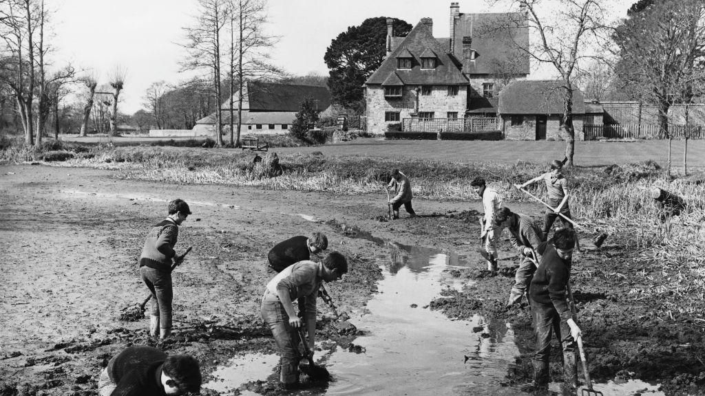 A black and white photo of boys cleaning the moat at Michelham Priory