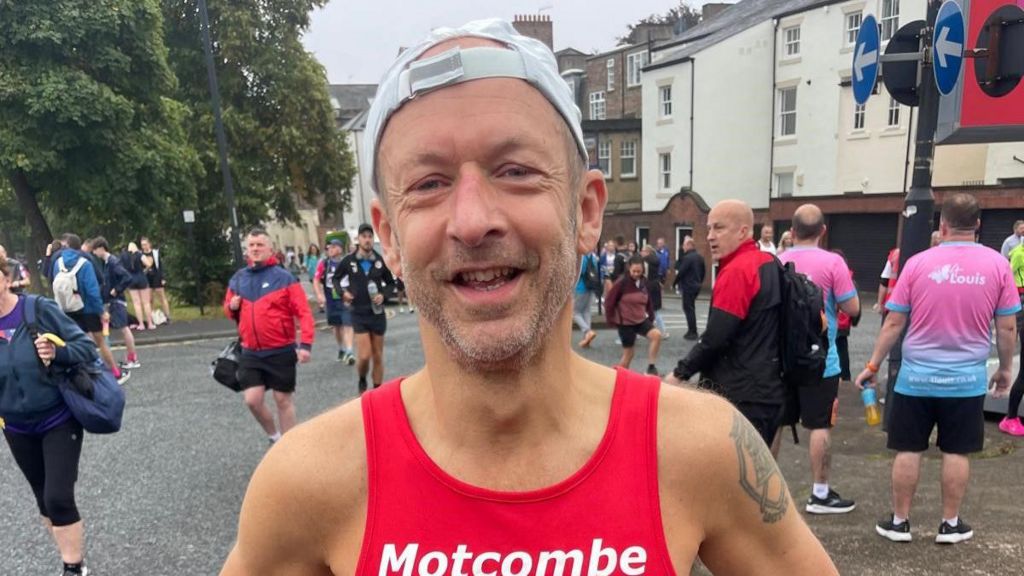 Vaughan Armstrong ahead of the Great North Run start. He is smiling and wearing a red shirt and white cap.