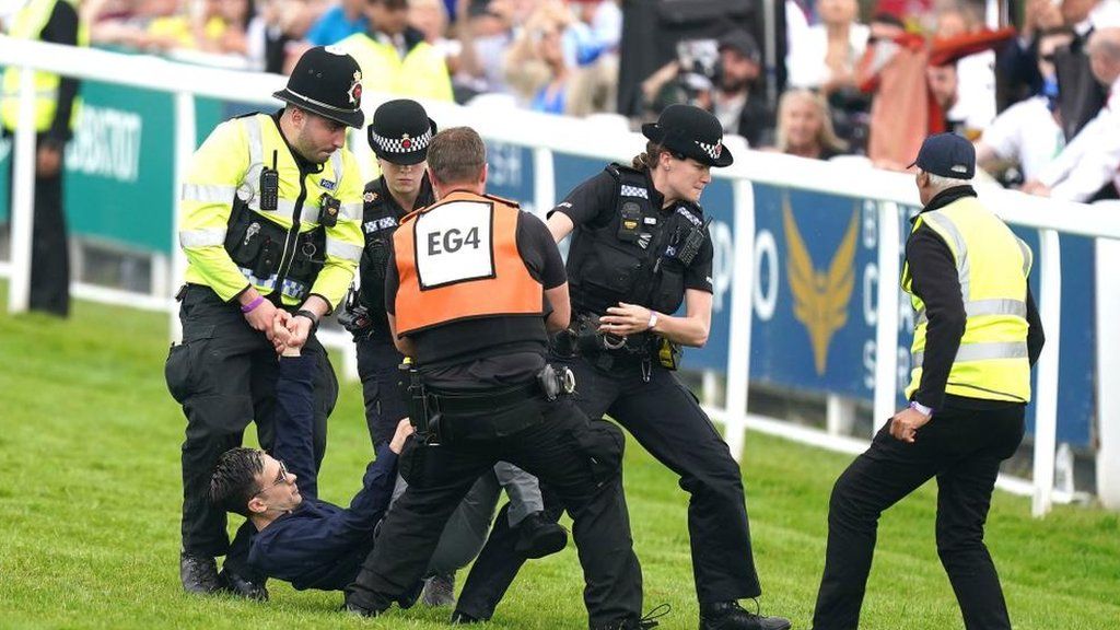 A protester being carried off the Epsom racecourse