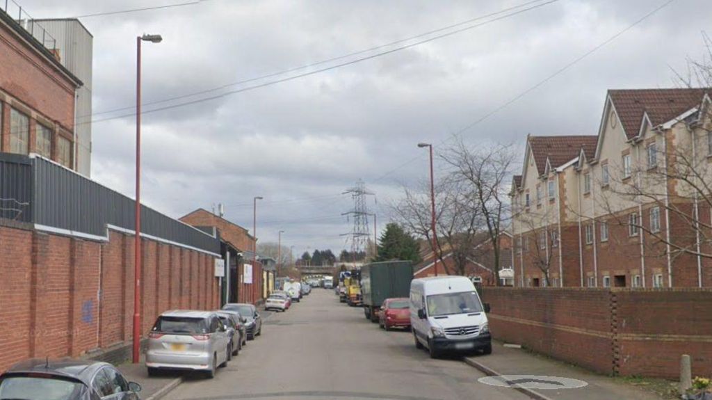 Industrial and residential street with cars parked on both sides