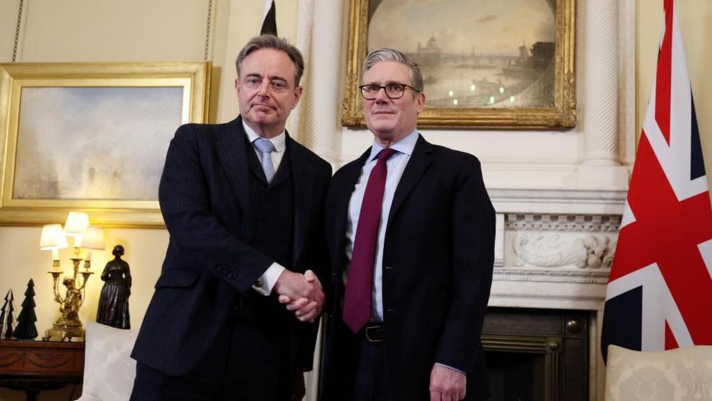 Belgian Prime Minister Bart De Wever, on the left in a dark three-piece suit visits 10 Downing Street and shakes hands with Sir Keir Starmer, wearing a maroon tie