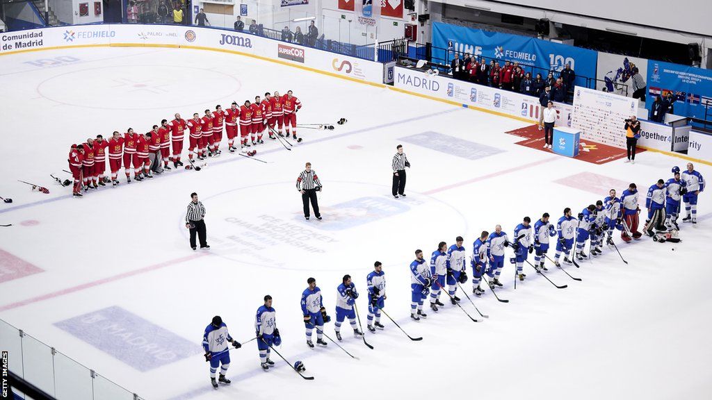Israel ice hockey team wearing blue, standing opposite the Georgia ice hockey team in red