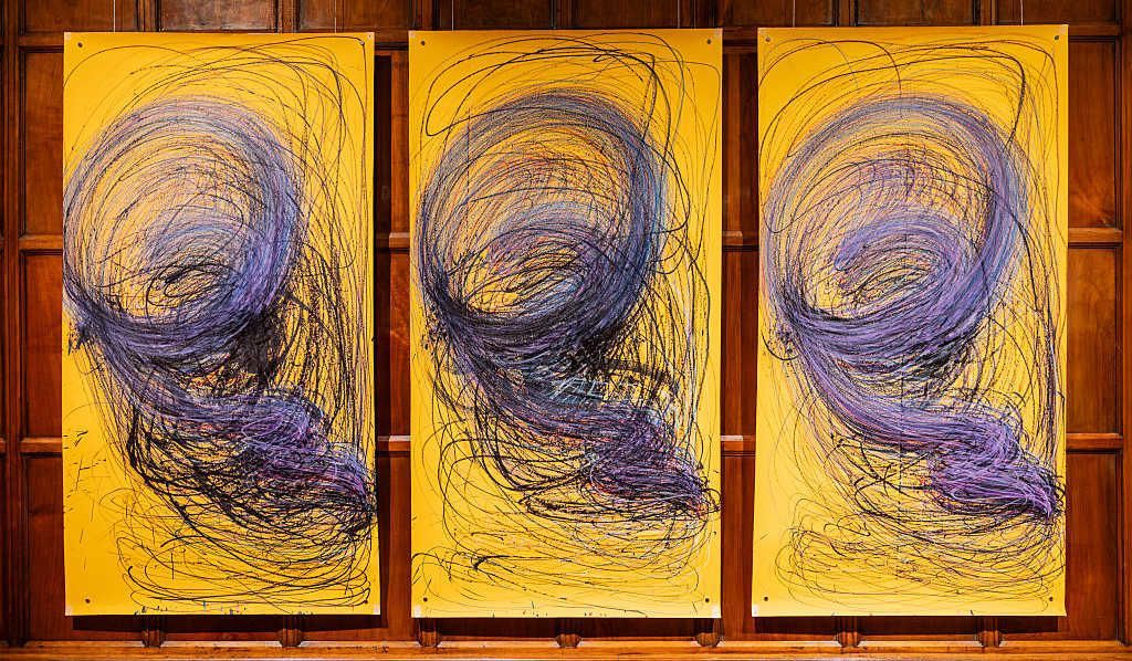 Three large yellow paintings by Nnena Kalu in in a row with identical blue and black swirly patterns 