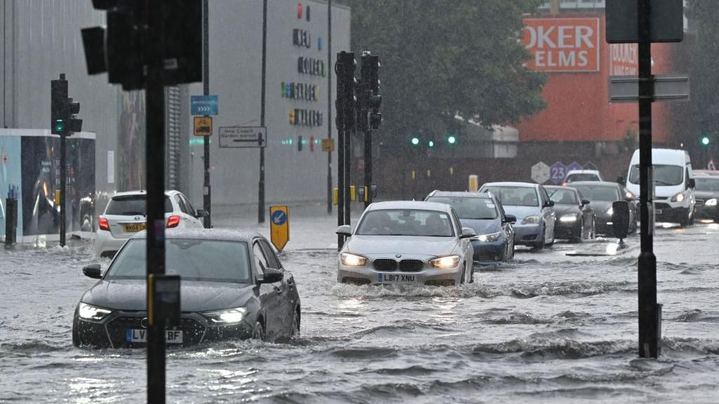 Cars driving through flood waters in central London
