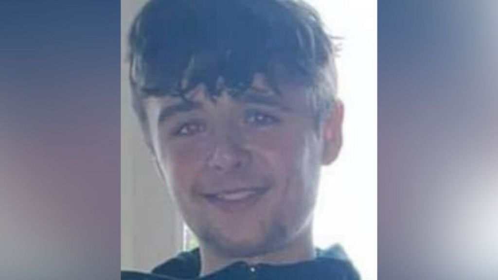 Young man with long hair smiling at camera