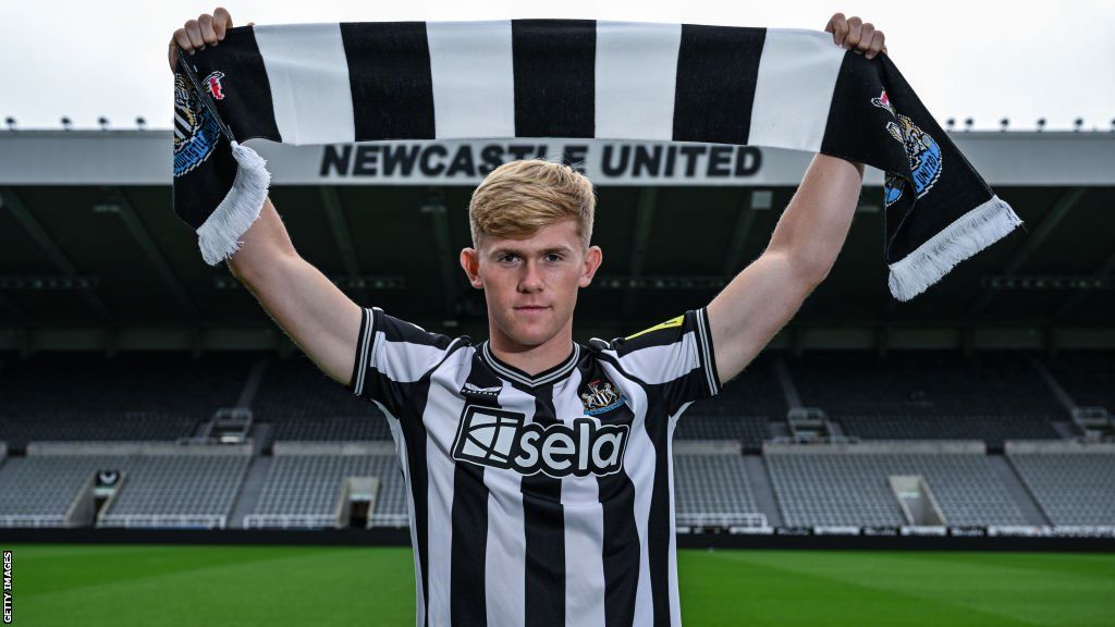 Lewis Hall poses for photos wearing a home shirt and scarf at St. James' Park