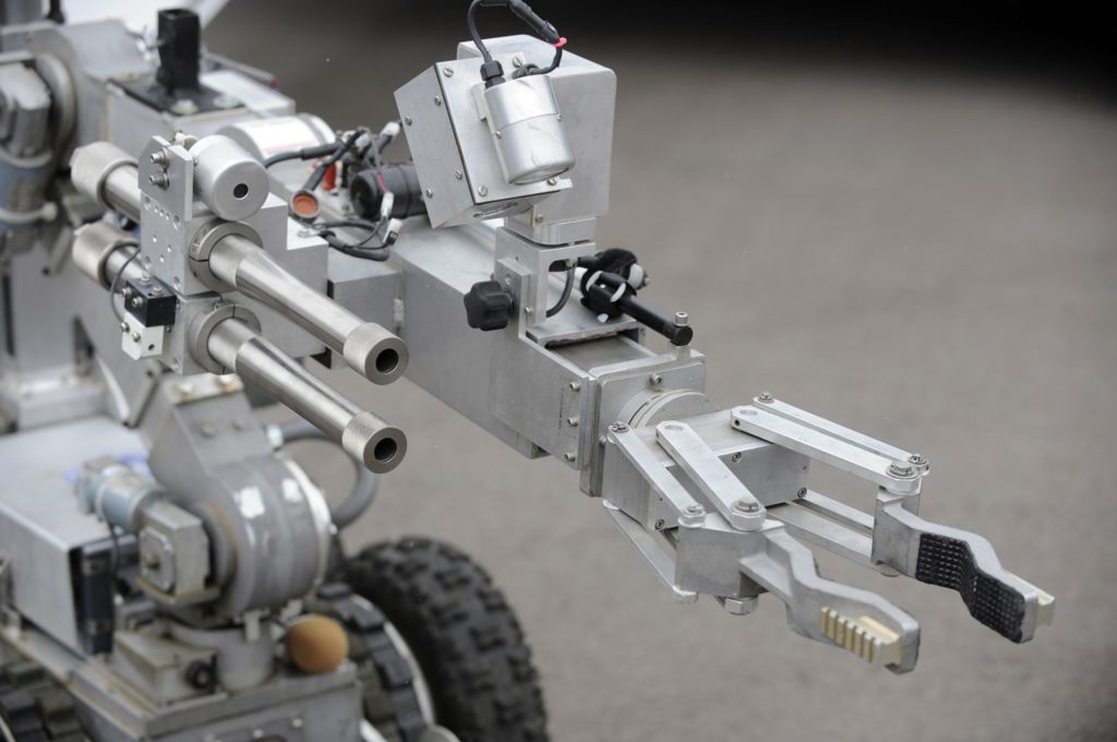 A bomb disposal robot extends its arm